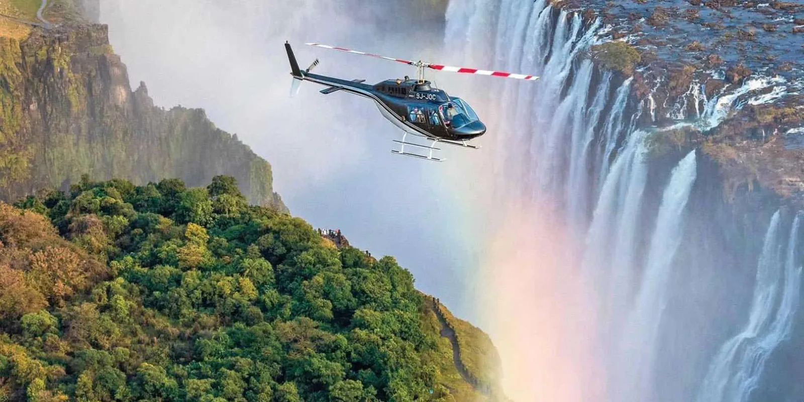 Wide aerial view of Victoria Falls showing the full curtain of water and rising mist column